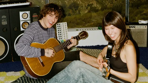 Two people sitting on the floor playing guitar