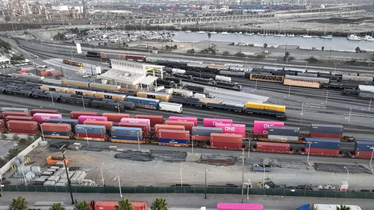 Aerial view of shipping containers on trucks and rail cars near a port.