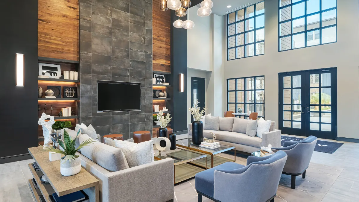 Chairs, windows and a television in an open apartment building lobby.