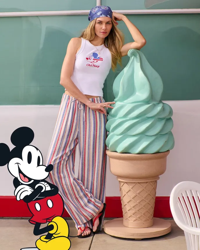 A person wears clothing from the Disney and Old Navy collection while outside of an ice cream shop.