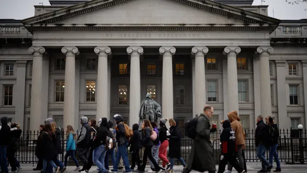 Crowds walk past a statue of a man outside a government building