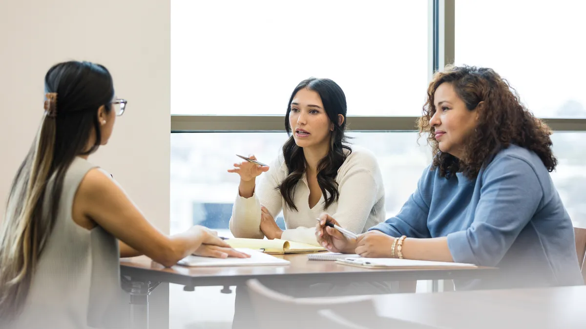 two executives interview a job applicant seated across each other in an office setting