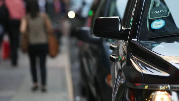 An SUV with an Uber sticker waits for a customer on a busy street.