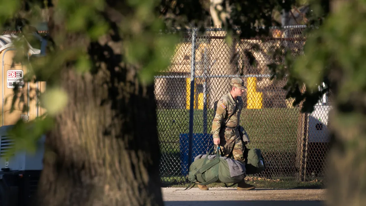 An individual approaches an Army training facility carrying a duffel bag.