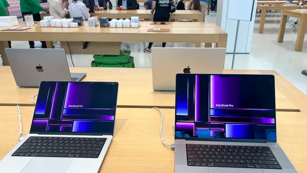 Laptops on display on a beige table in a store.