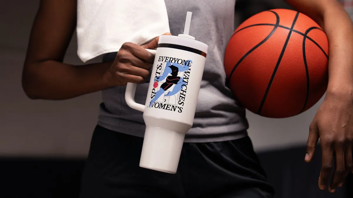 Person holding a white Stanley 1913 tumbler and holding a basketball