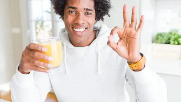 Person holding glass of orange juice