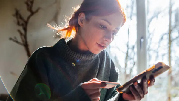 Woman shopping online with laptop and credit card on hand.