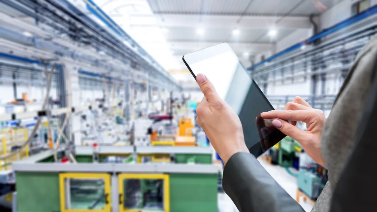 A person standing on top of a balcony and checking inventory of a manufacturing company on a touchscreen tablet.