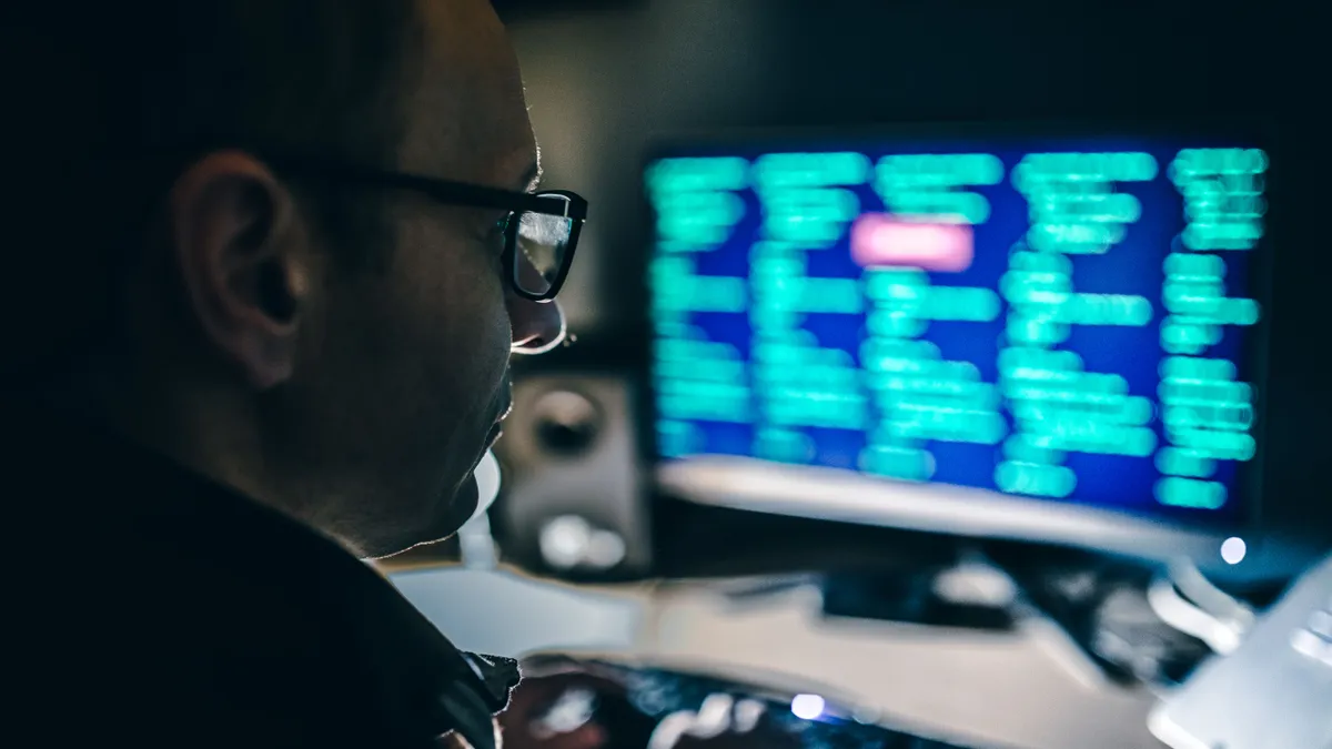 A man looks at lines of code depicted on a computer screen