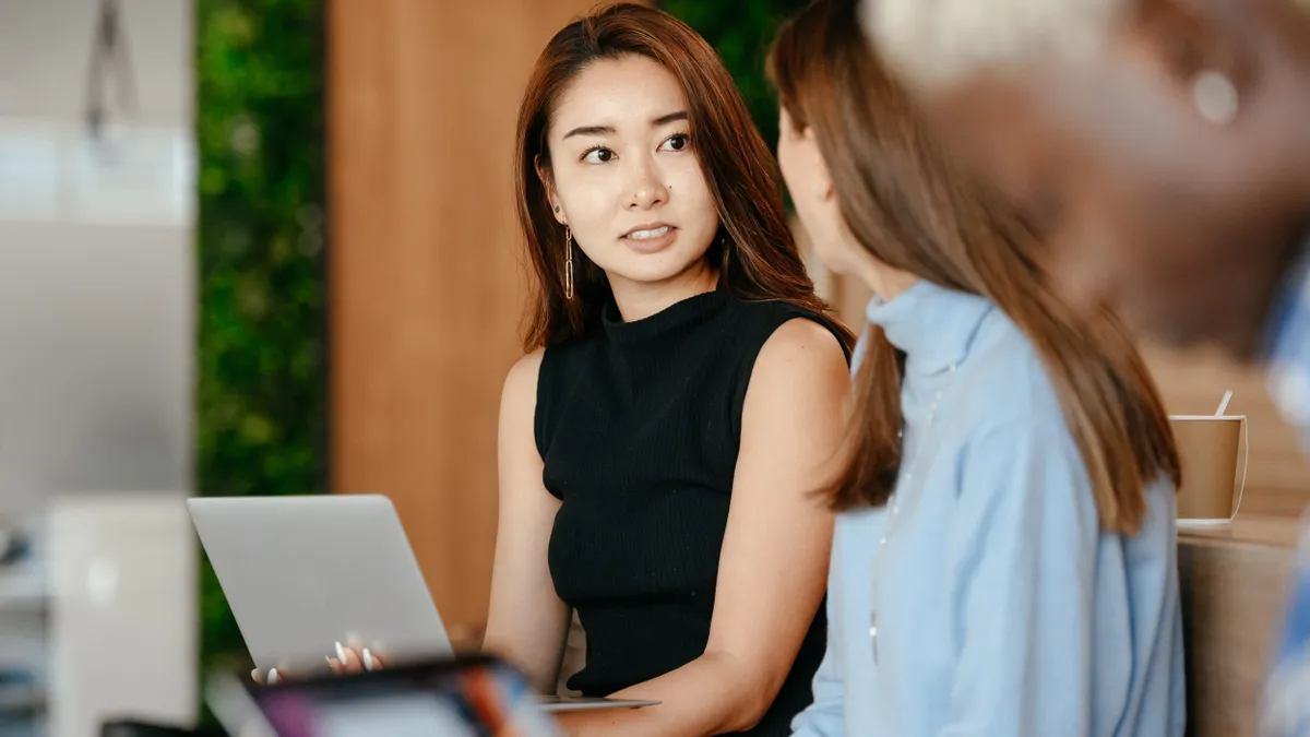 A distressed Asian person looks at their co-workers