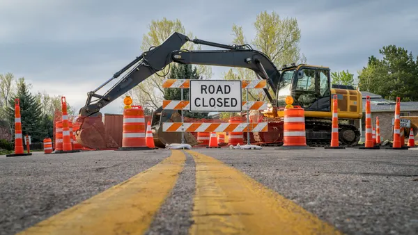 Road closed sign and barrier on a residential street for construction.