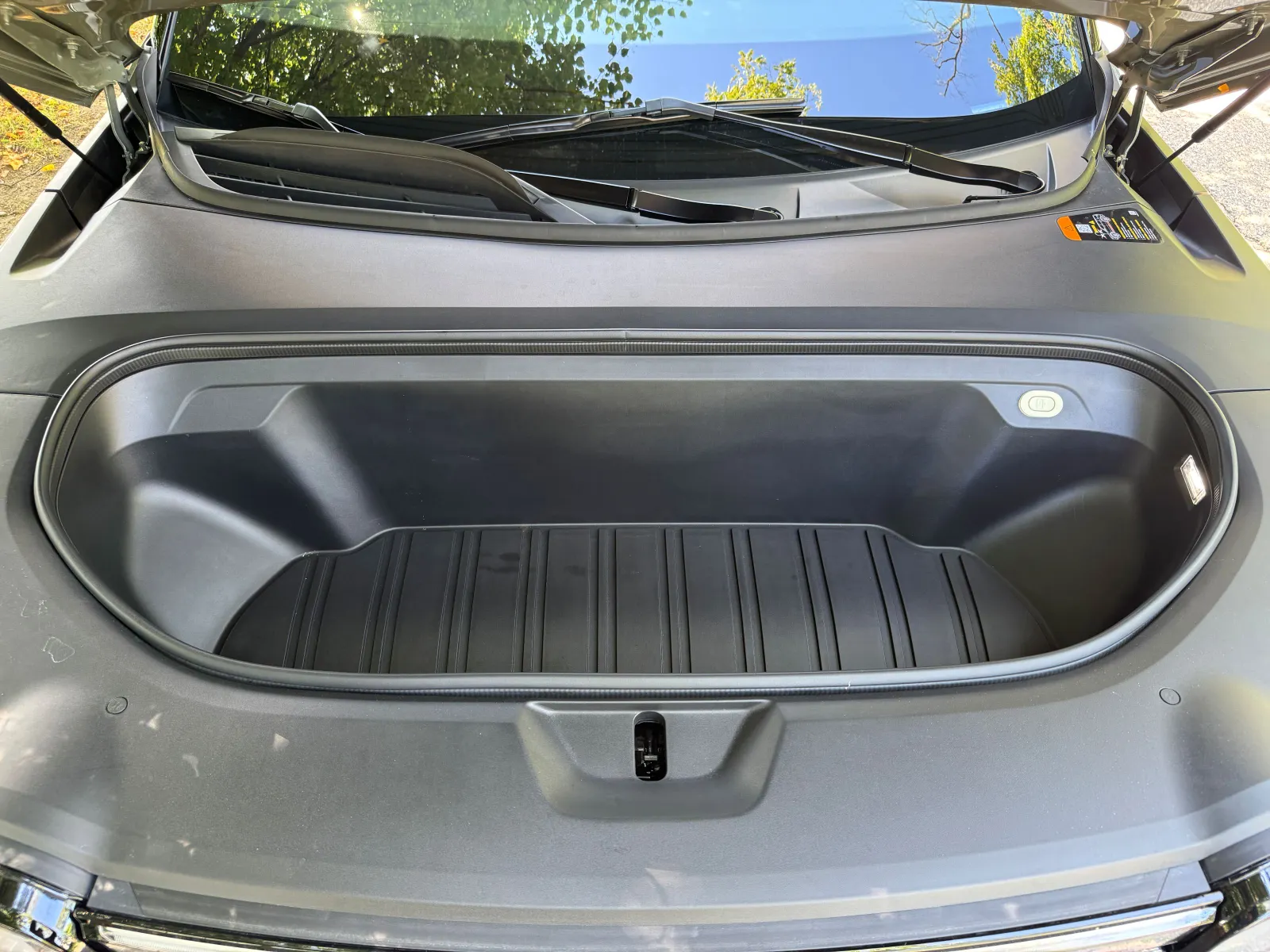 A vehicle's open frunk is shown. A frunk, otherwise known as a front trunk, is common in electric vehicles