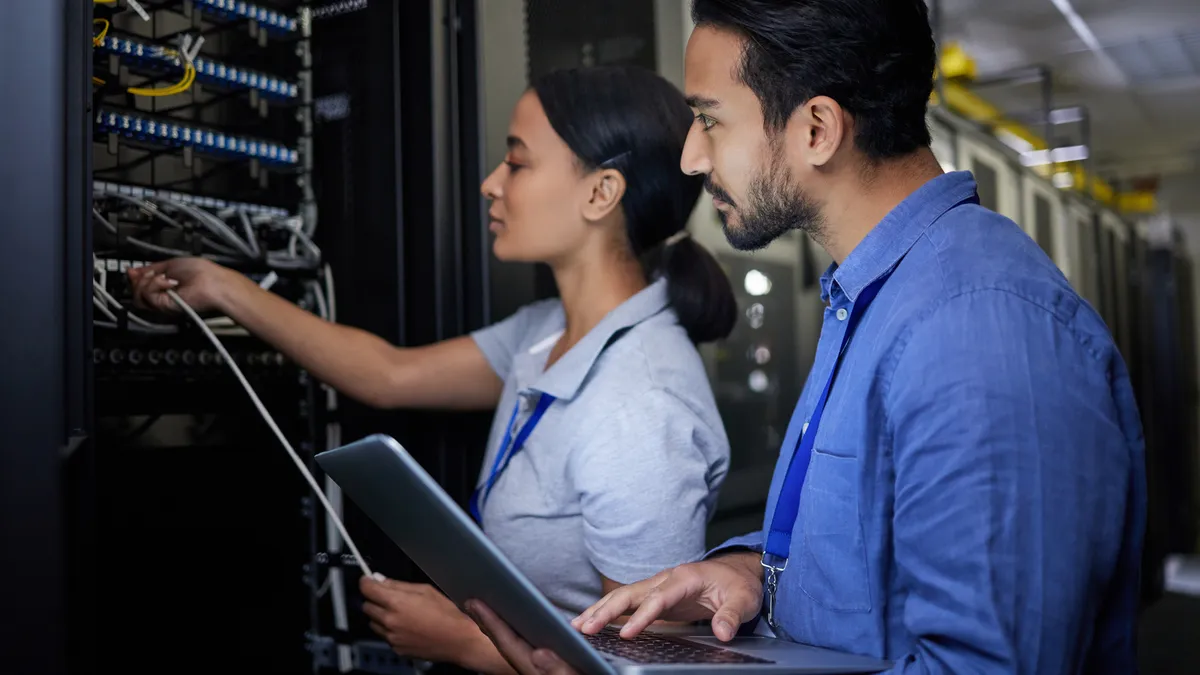 People examining a computer server with a laptop