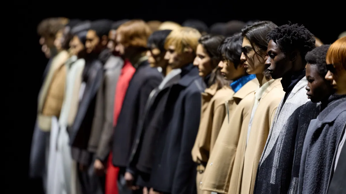 Models stand in a line on a darkened runway.