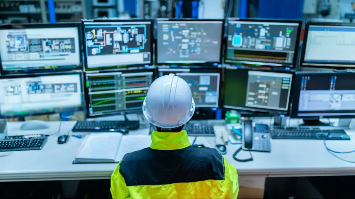 Person wearing hard helmet looking at data on monitors