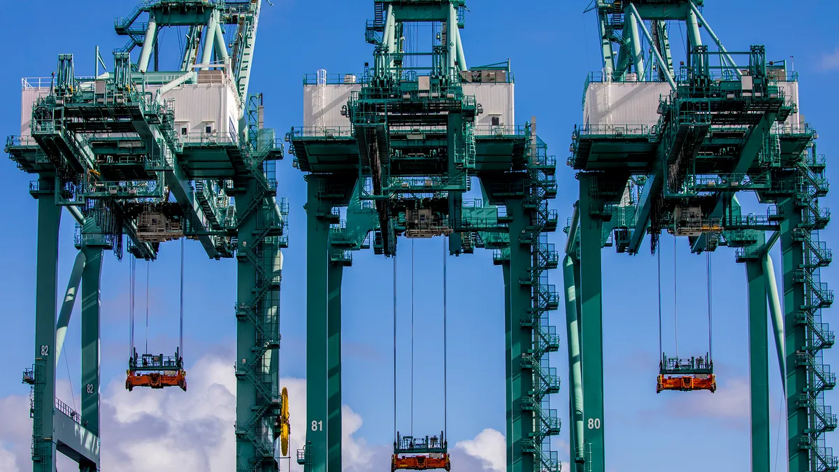 Container cranes against a cloudy sky.