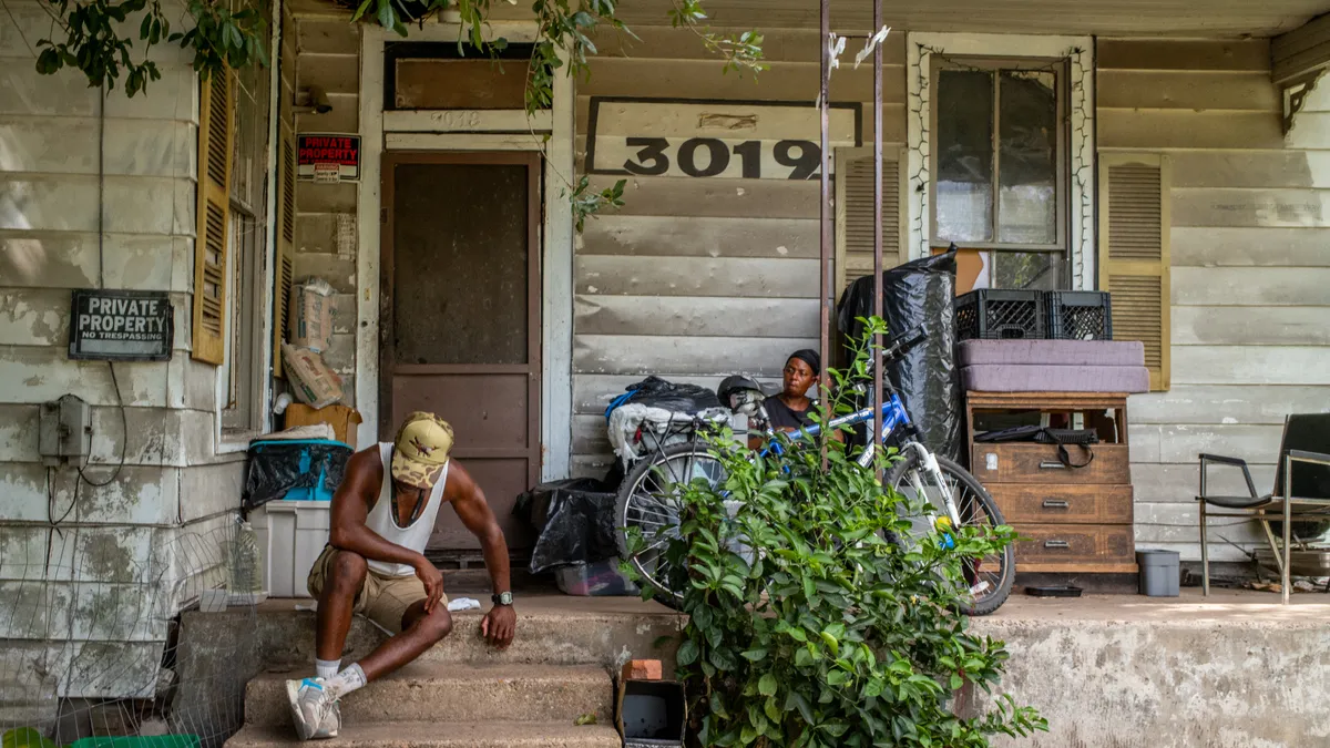 A person sits on the front steps of a house in Houston during a heat wave.