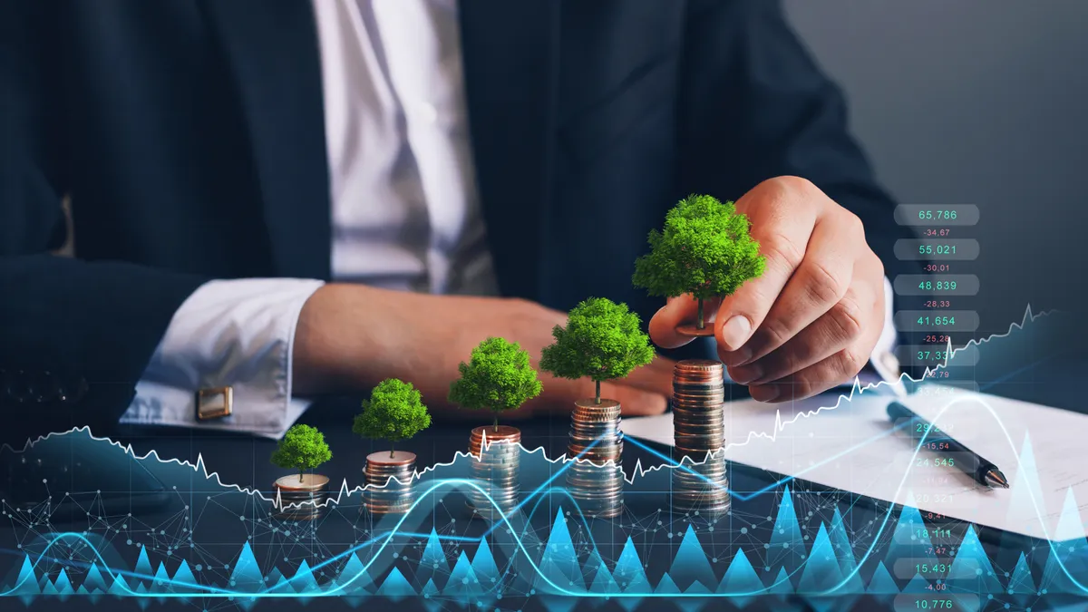 Businessman holding coin with tree growing on money coin stack and digital growth graph.