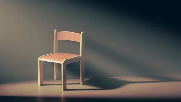 An empty chair sits in a dark room. Nothin else is in the room