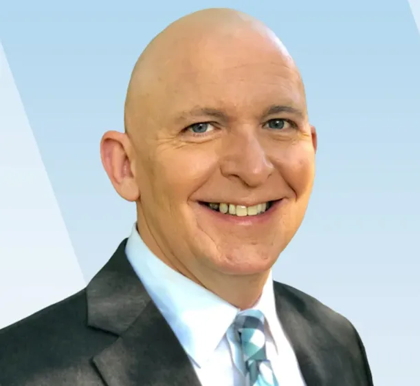 Headshot of a smiling bald man in a suit and a blue patterned tie.