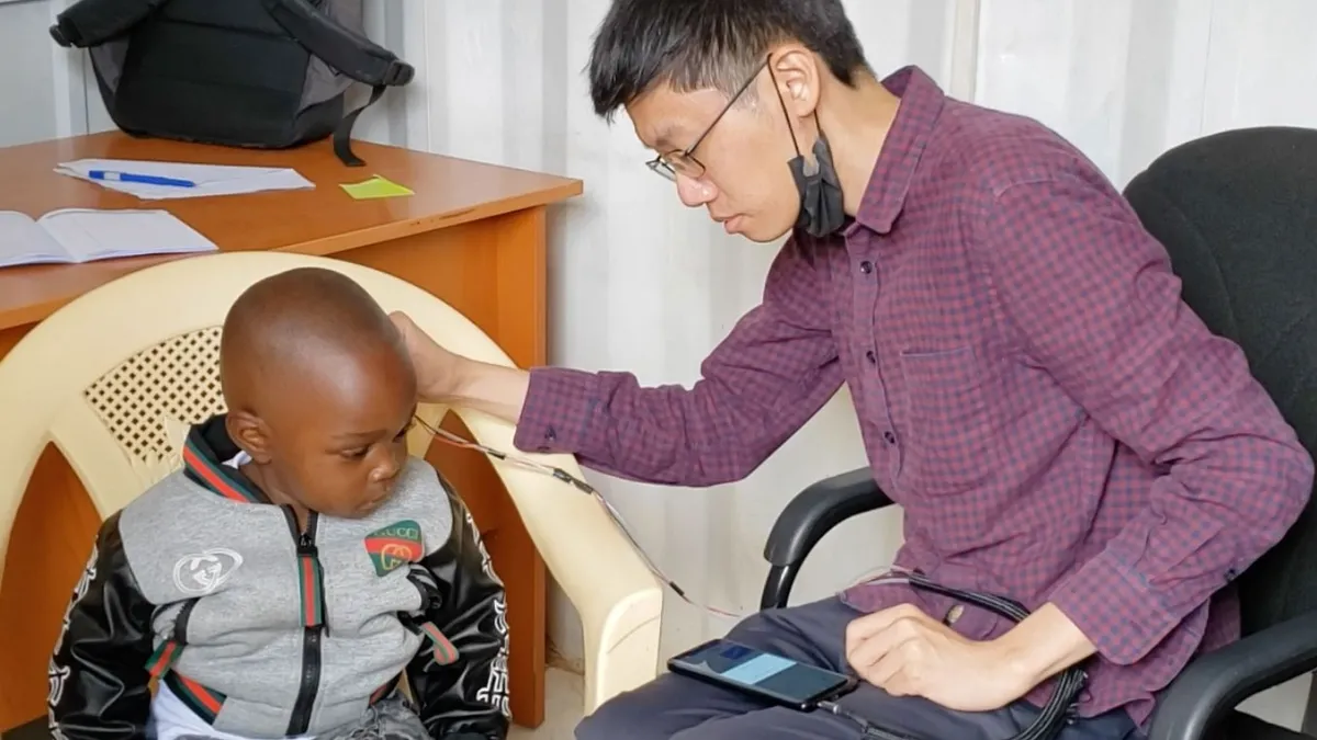 A man conducts an innovative and low-cost hearing test on a child