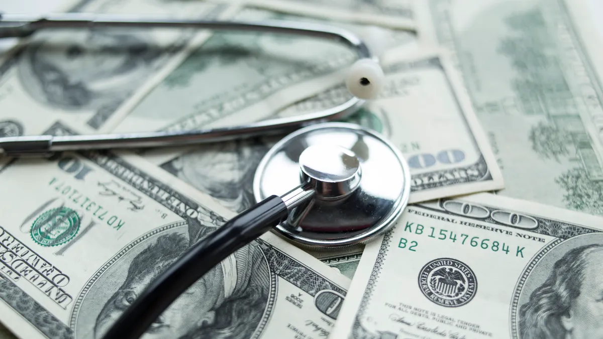 A stethoscope rests on a pile of $100 bills.