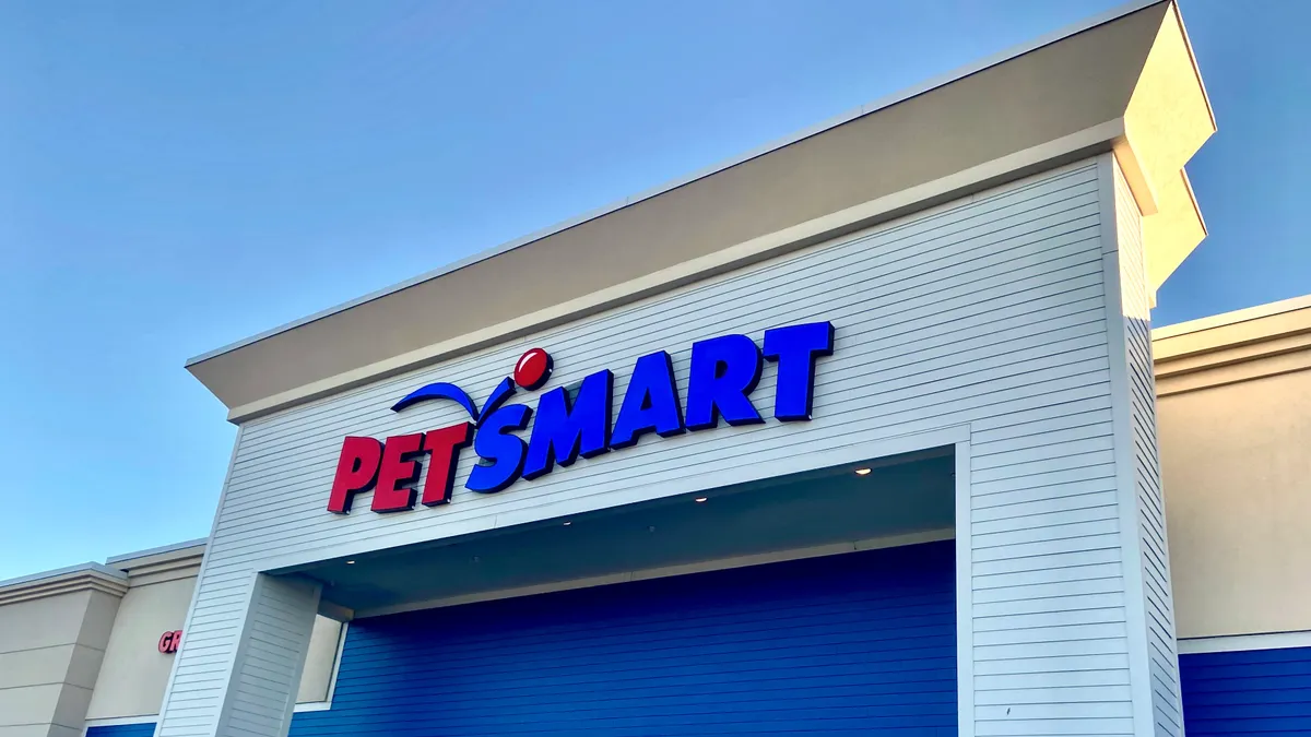 The brand name PetSmart, written as one word, with "pet" in red and "smart" in blue, is the banner on the outside of a store with a white clapboard entrance.