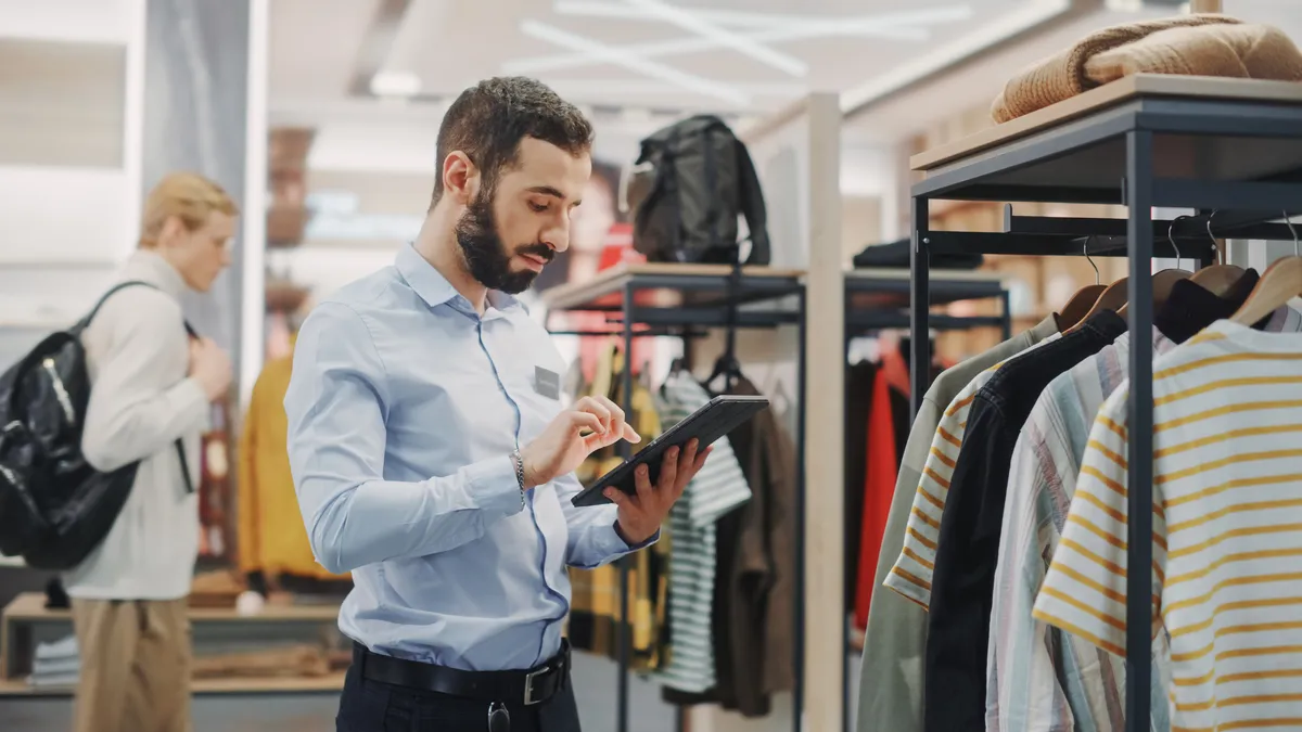 Retail manager observing inventory with tablet.