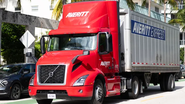 An Averitt tractor-trailer making a delivery in Miami with palm trees and a passenger car in the background.