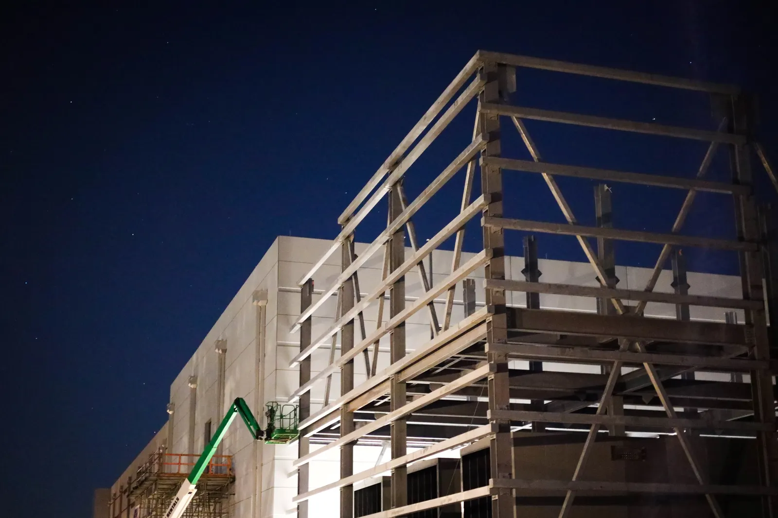 A white data center under construction is seen under a night sky with stars.