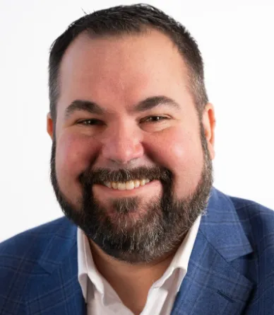 Man in dark suit smiling.