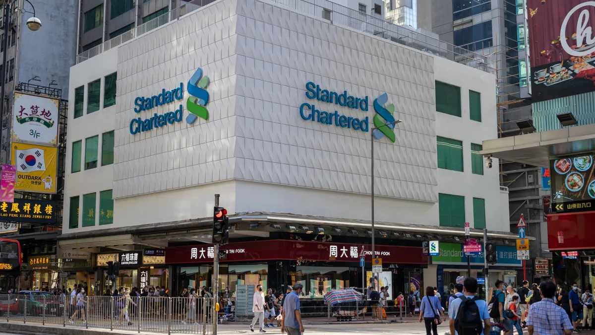 October 4, 2021 : People walk past the Standard Chartered Bank in Mong Kok, Kowloon, Hong Kong.