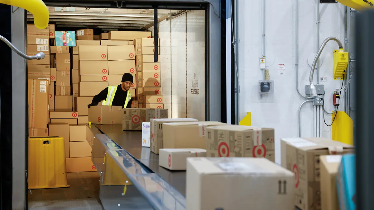 A person loads boxes onto a conveyor belt.