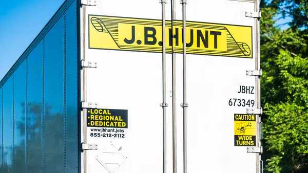 A J.B. Hunt trailer on I-66 in Virginia with tree branches in the background.