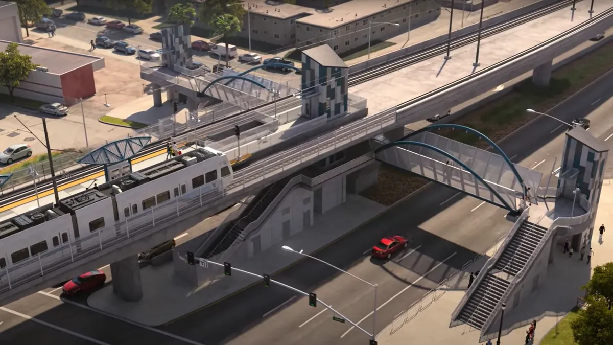 An aerial view of a light rail station, with a train pulling up from the right.