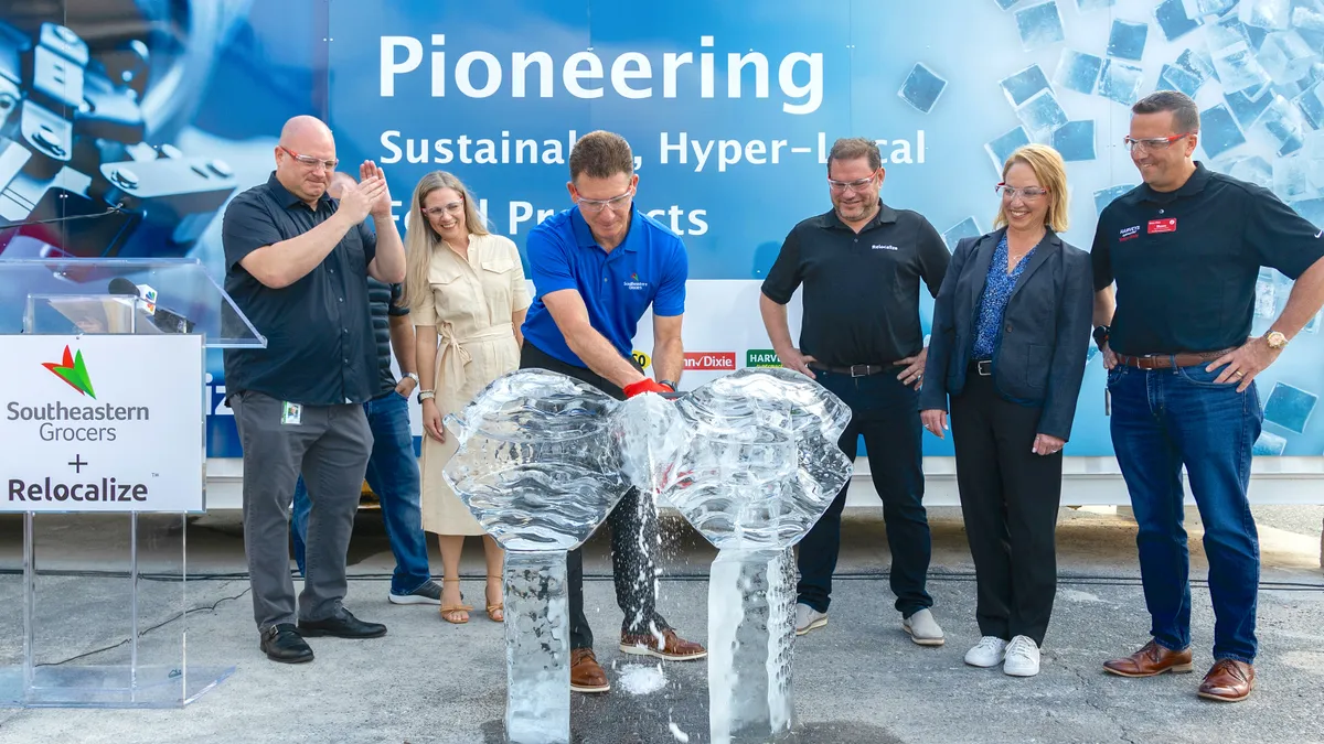 Group of people at a ceremonial ribbon cutting, but the ribbon is created out of 200 pounds of ic e