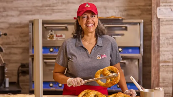 A restaurant worker holding a pretzel.