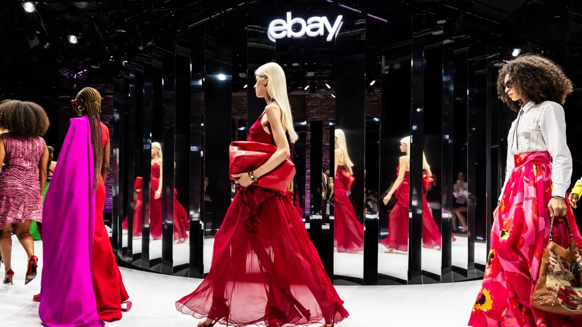 Models wearing bright colors walk the runway in front of mirrors.