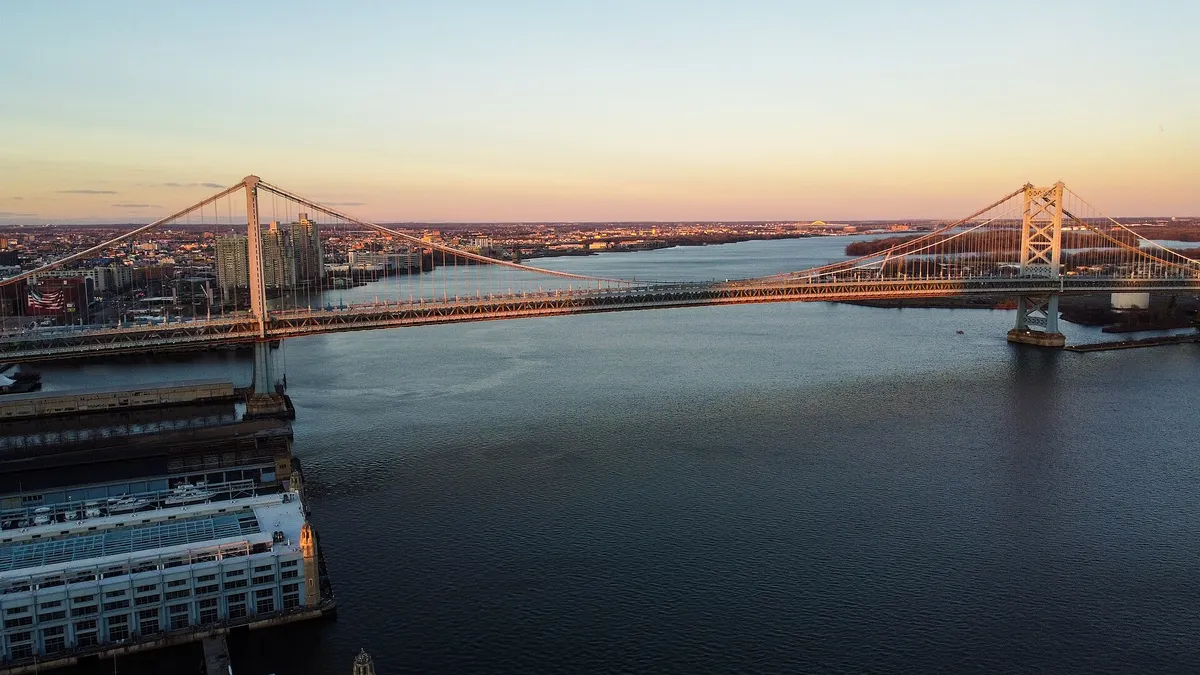 A wide shot of a bridge going over water at sunset.