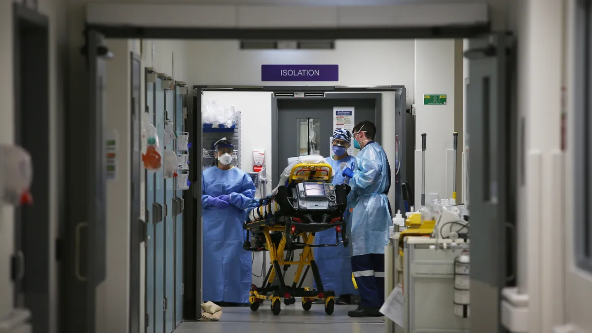 A medical team takes a patient into the isolation ward in the emergency department of a full-service acute hospital facility.