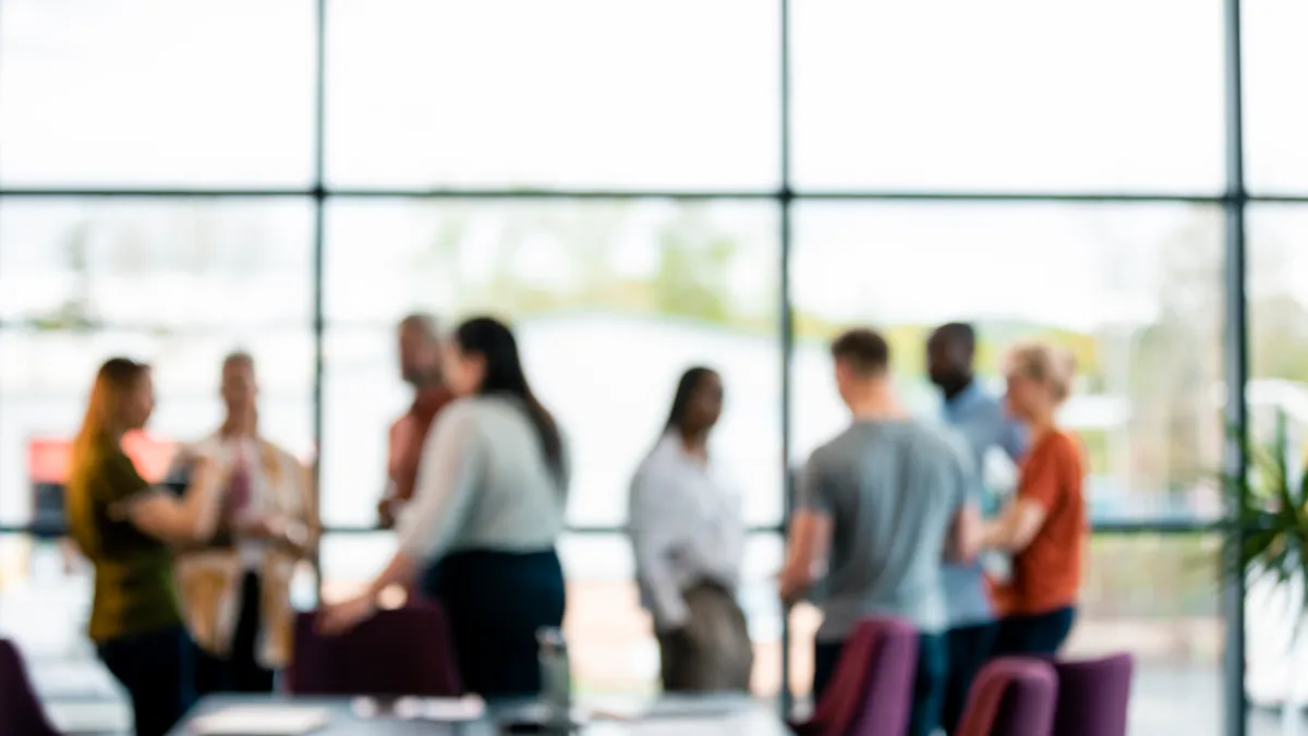 An out-of-focus background of a group of people stood in a boardroom