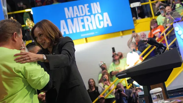 Kamala Harris greets a person in a bright yellow shirt at a campaign event.