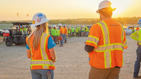 Man and woman wearing construction vest and hard hat