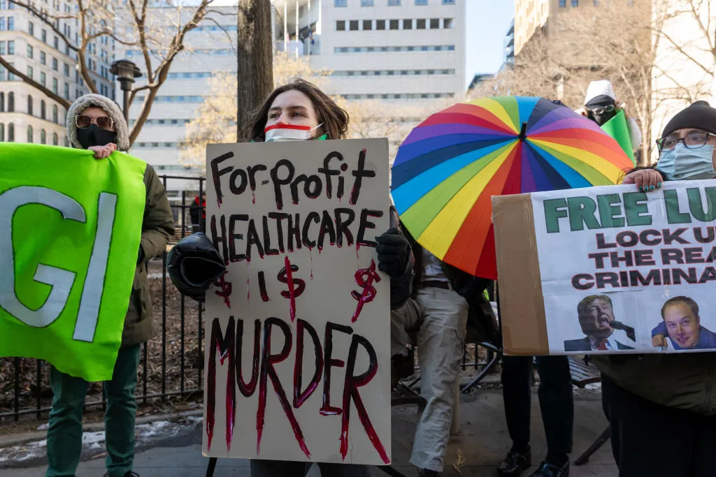 A female protester holds a sign reading "For-profit healthcare is murder" outside of a courthouse.