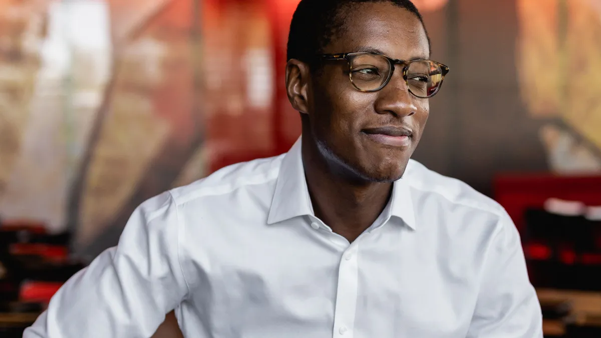 A photograph of a man wearing a white dress shirt looking to the right.