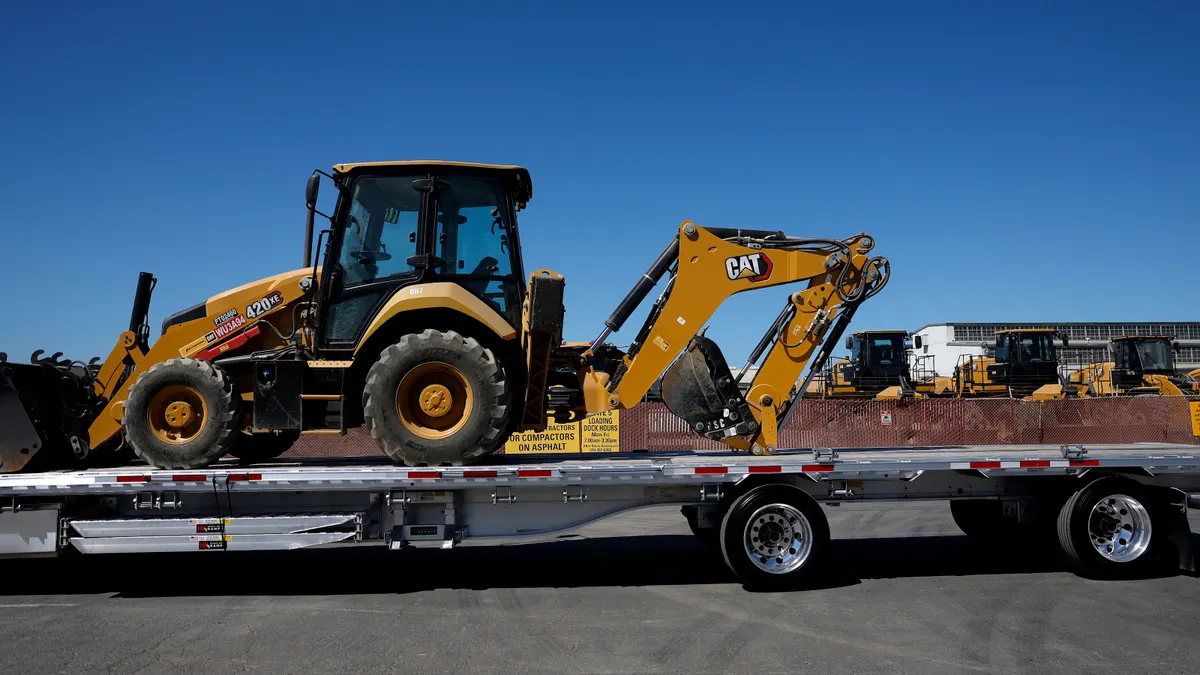 A Caterpillar backhoe sits on a trailer