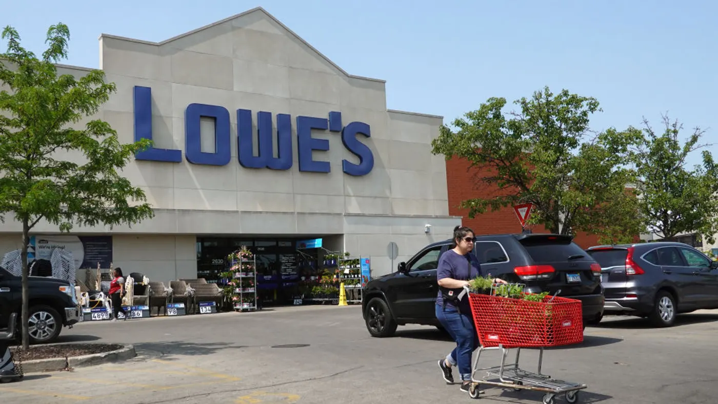 A customer pushes a cart outside a Lowe's store.