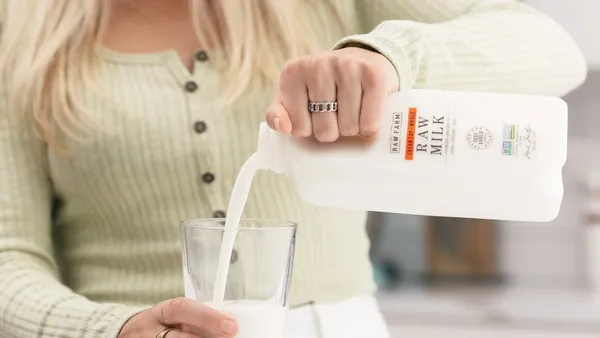 A close up of a woman pouring raw milk into a glass