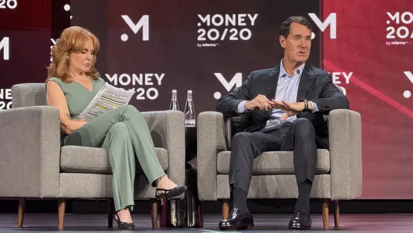 A woman interviews a man in professional attire on stage.